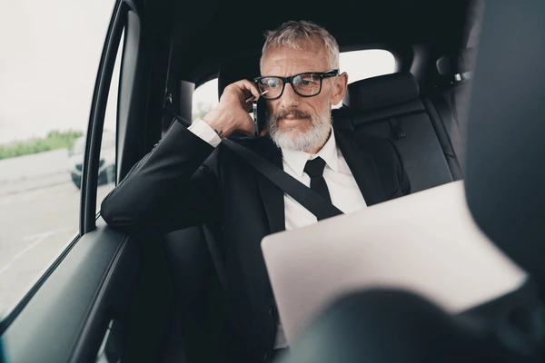 Corporate Travel Sydney executive using laptop in luxury chauffeur car with Riff Chauffeur Cars during business transfer